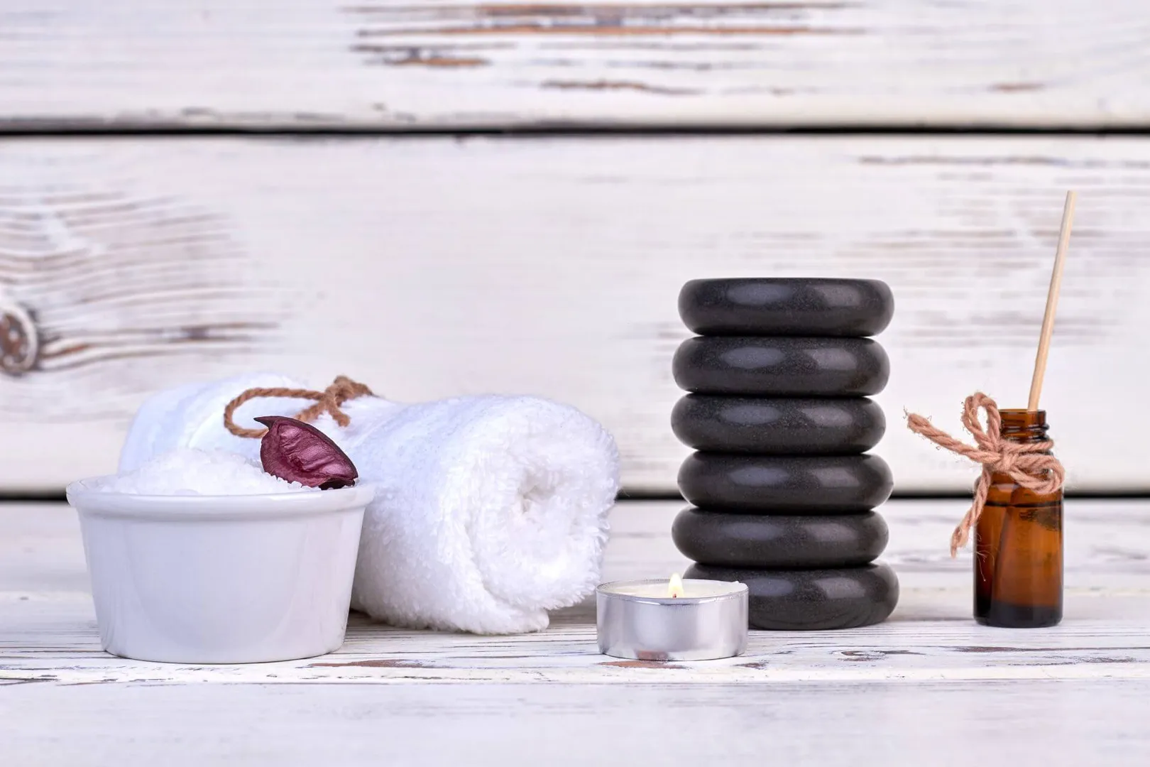 Spa items: towel, stones, candle, and oil bottle.